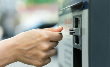 Closeup of female hand with a credit card and ticket vending machine